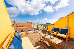 En tagterrasse med træmøbler, et bord og en lygte.