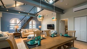 A spacious living area with a wooden dining table, sofas, and a staircase. - NEW The Yellow House - Renovated Monumental Penthouse (Willemstad)