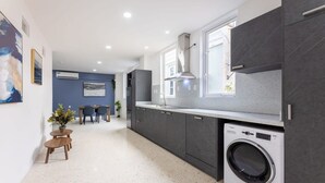 Una cocina moderna con armarios grises, lavadora incorporada y un comedor con mesa y sillas.