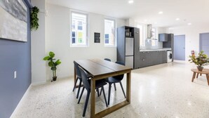 Una cocina moderna con comedor, ventanas amplias y una planta en maceta.
