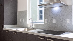 Une cuisine moderne dotée de plans de travail en granit, d’un évier en acier inoxydable et d’une fenêtre située au-dessus de l’évier.
