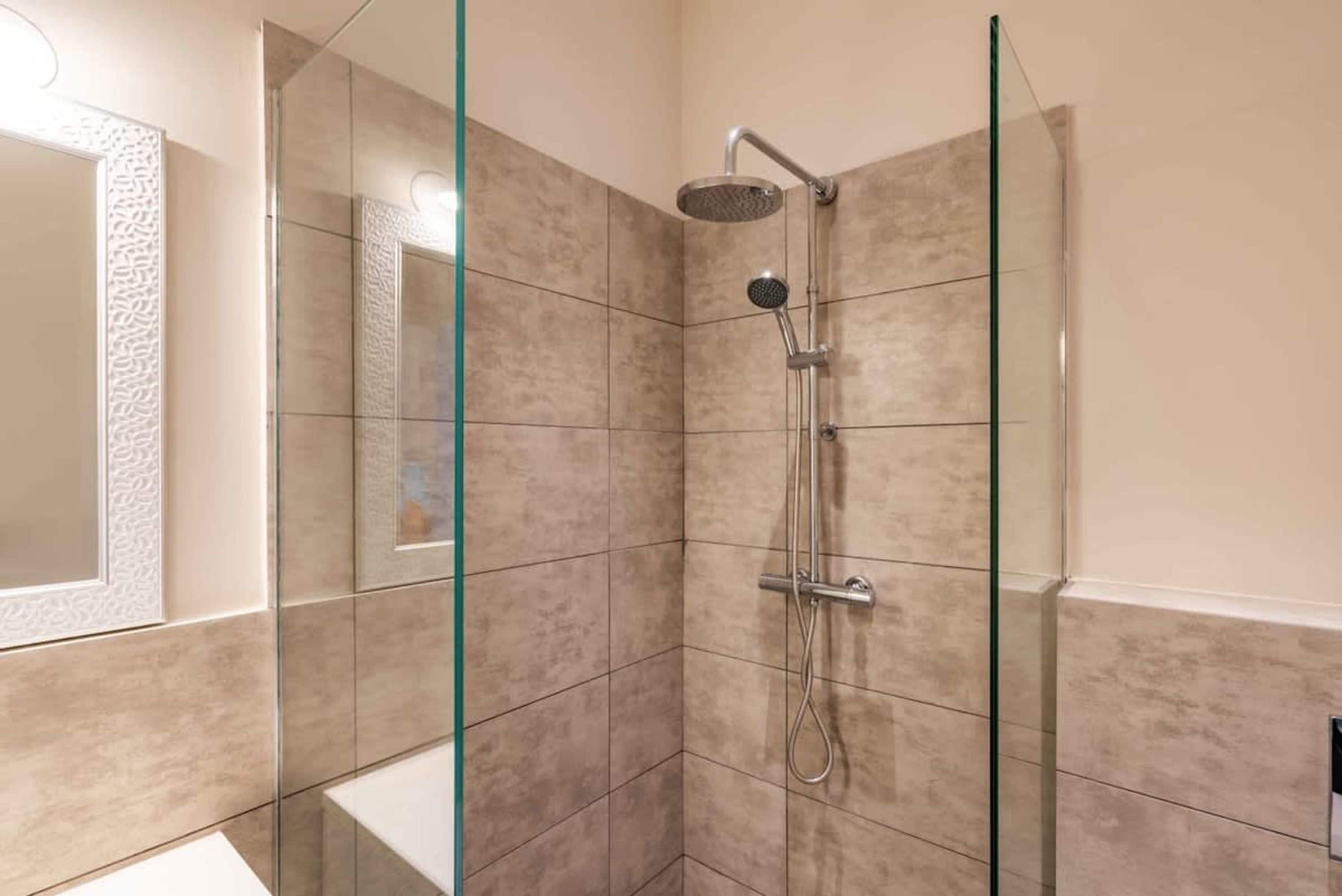 Un baño moderno con cabina de ducha de vidrio, ducha de mano y grifo empotrado.