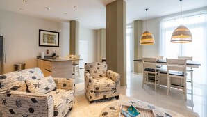 A modern living room with a sofa, armchair, and dining area with chairs and a table. - Fabulous Chic Apartment Filled w Natural Light at Famous Handelskade (Willemstad)