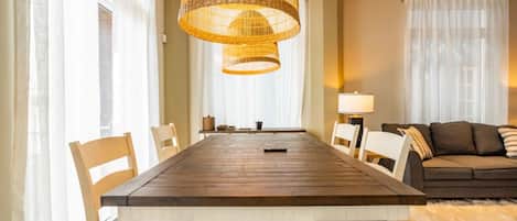 A dining area with a wooden table, white chairs, and a woven pendant light fixture.