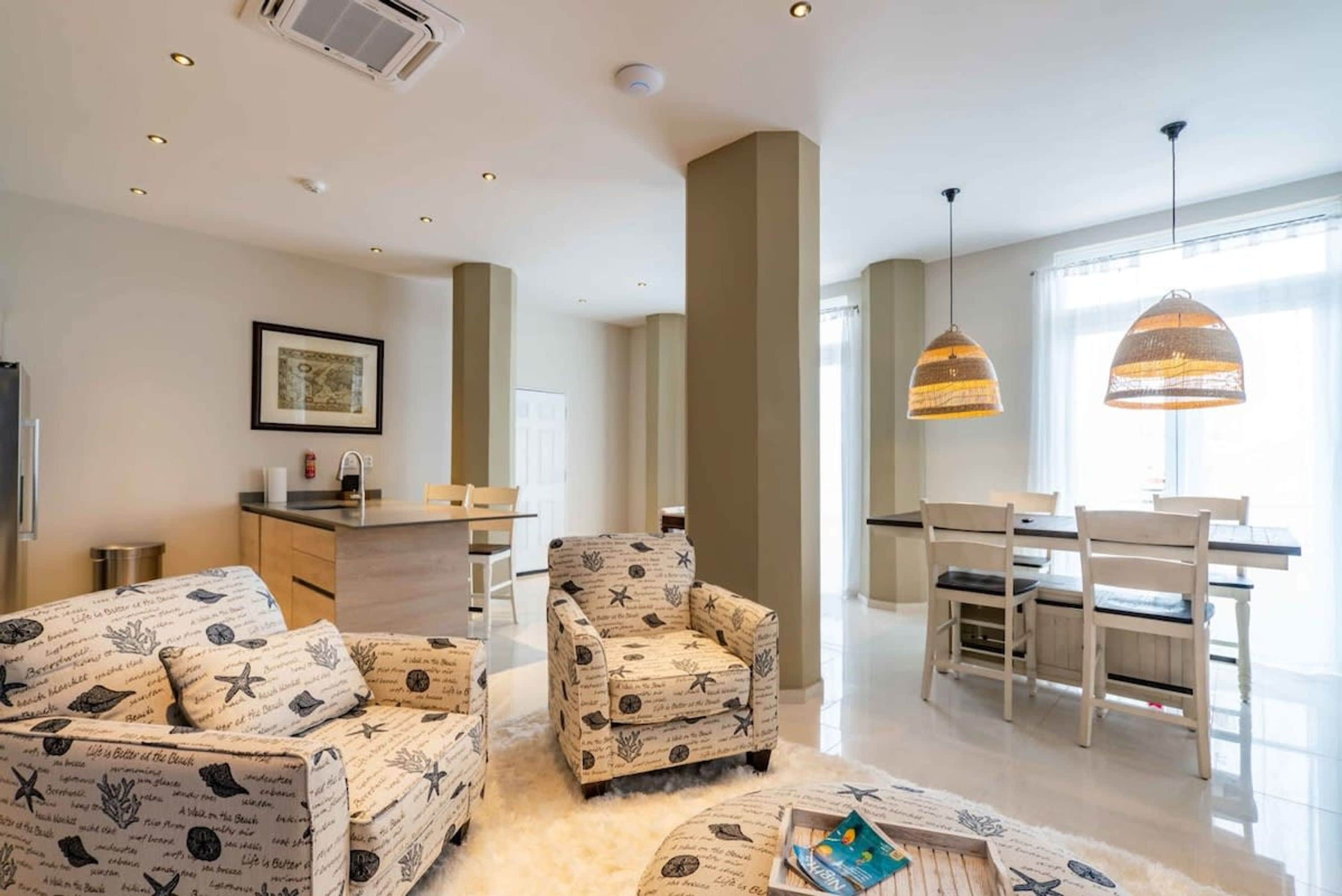 A modern living room with a sofa, armchair, and dining area with chairs and a table.