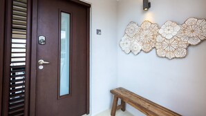 Une porte en bois avec un panneau de verre, un banc et un mur orné de motifs décoratifs découpés.