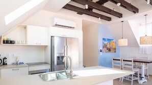 A modern kitchen with a central island, stainless steel appliances, and a hanging light fixture.