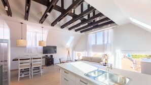 A modern kitchen with a large island, wooden beams on the ceiling, and a view of the outside.