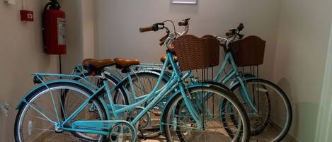 A teal bicycle with wicker baskets and brown leather seats parked indoors.