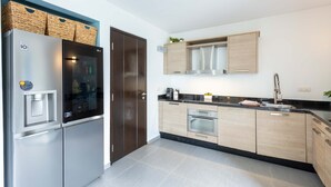 A modern kitchen with stainless steel appliances, wooden cabinets, and a black countertop. - Indigo Garden at Blue Bay Golf Beach Resort (Sint Michiel)