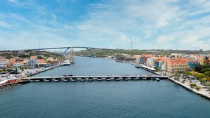 Un río con un puente, barcos amarrados a la orilla y edificios coloridos al otro lado.