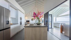 A modern kitchen with a central island, stainless steel appliances, and a view to the outside.