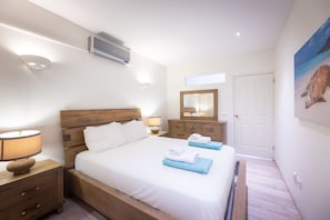 A bedroom with a bed, a nightstand, a dresser, a mirror, and a door. - Heart of the City Plaza Jojo Heritage Home (Willemstad)