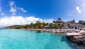 A coastal resort with a clear turquoise sea, a dock, and a thatched-roof building. - Spacious Bright Villa - Spectacular Ocean Views Private Pool (St. Marie)