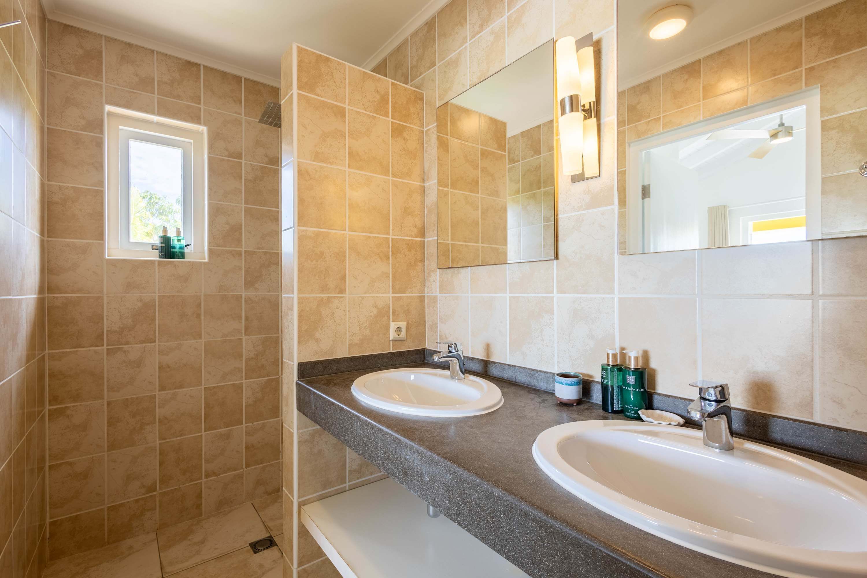 A bathroom with two sinks, a window, and a mirror.