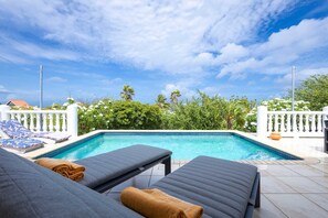 Une piscine avec des chaises longues et une clôture blanche.