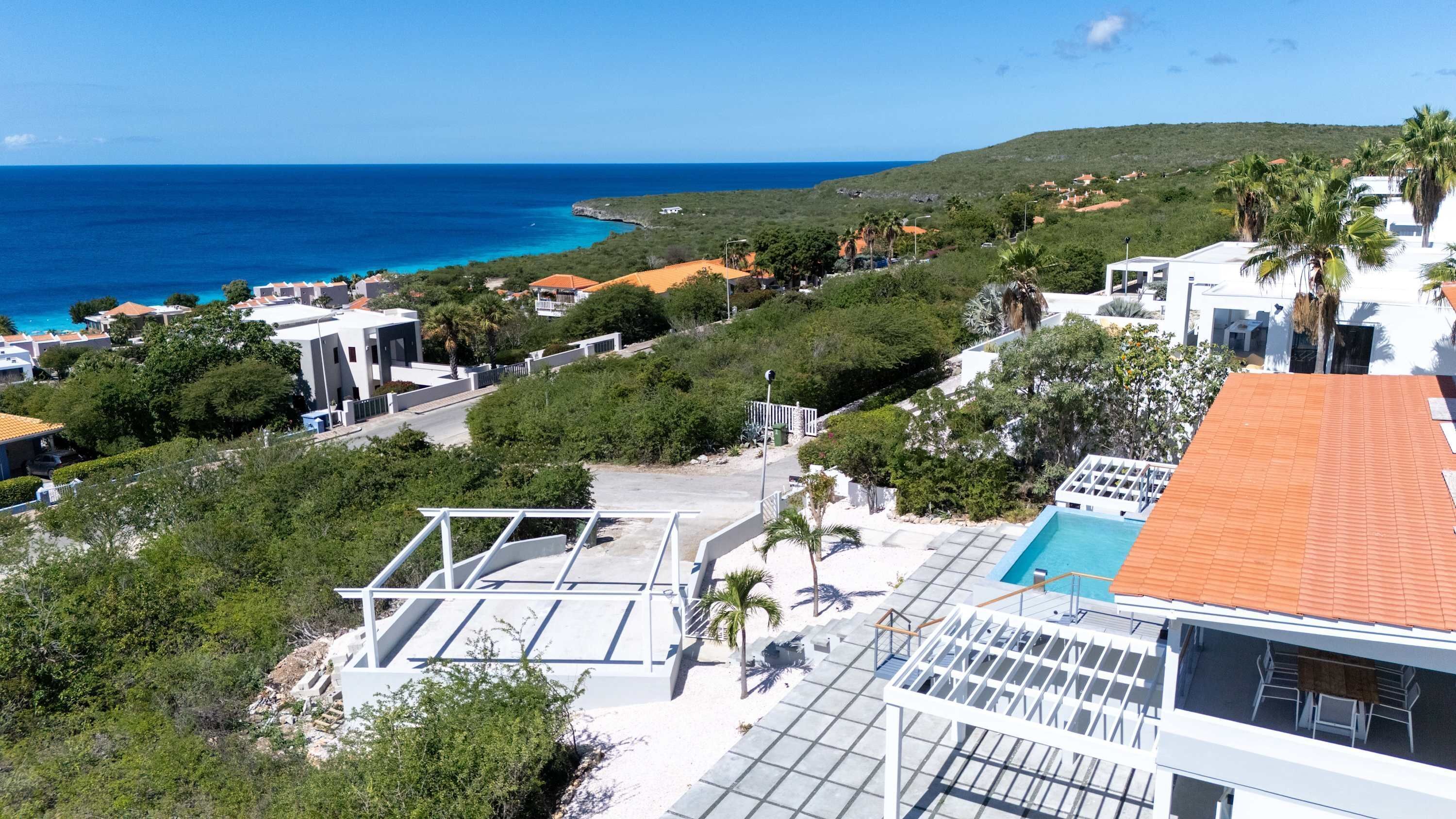 Un quartier résidentiel situé sur la côte, avec des maisons, une piscine et une vue sur l’océan.