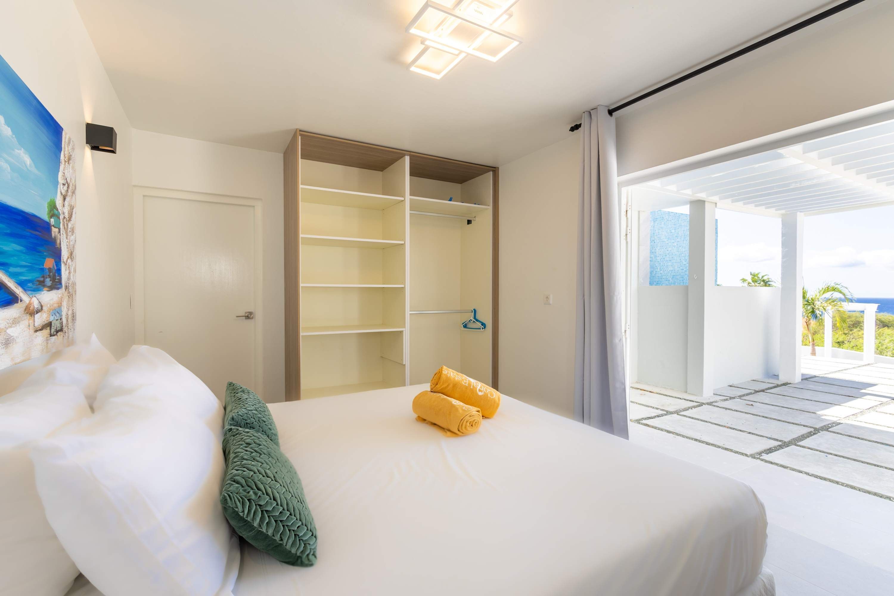 A hotel room with a bed, a wardrobe, and a view of the ocean.