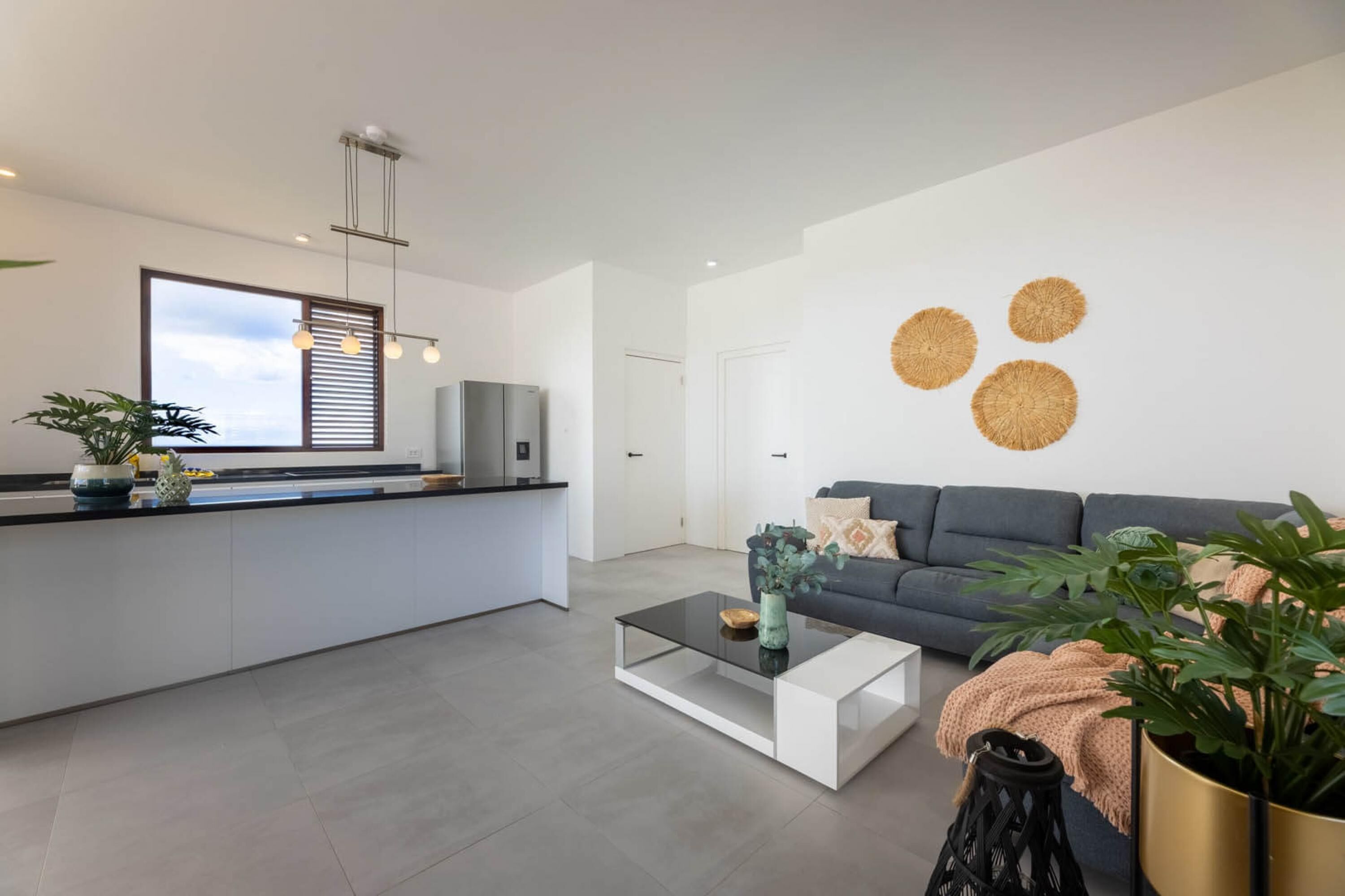 Un espace de vie moderne comprenant une cuisine, un coin repas et un salon avec un canapé et une table basse.