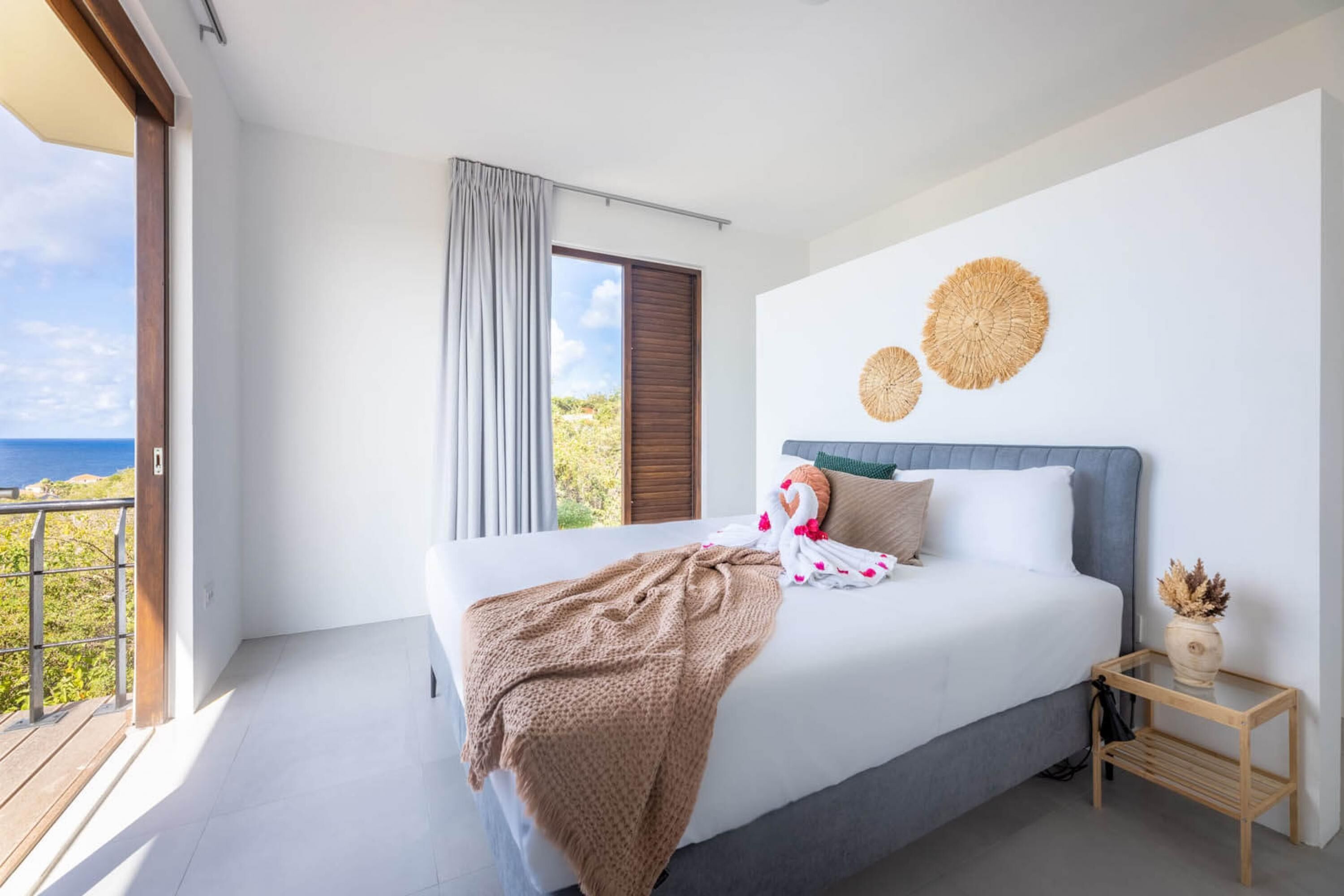 Un dormitorio con una cama grande, vistas al mar y un balcón.
