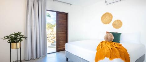 A modern bedroom with a bed, a potted plant, a sliding door, and a ceiling fan.