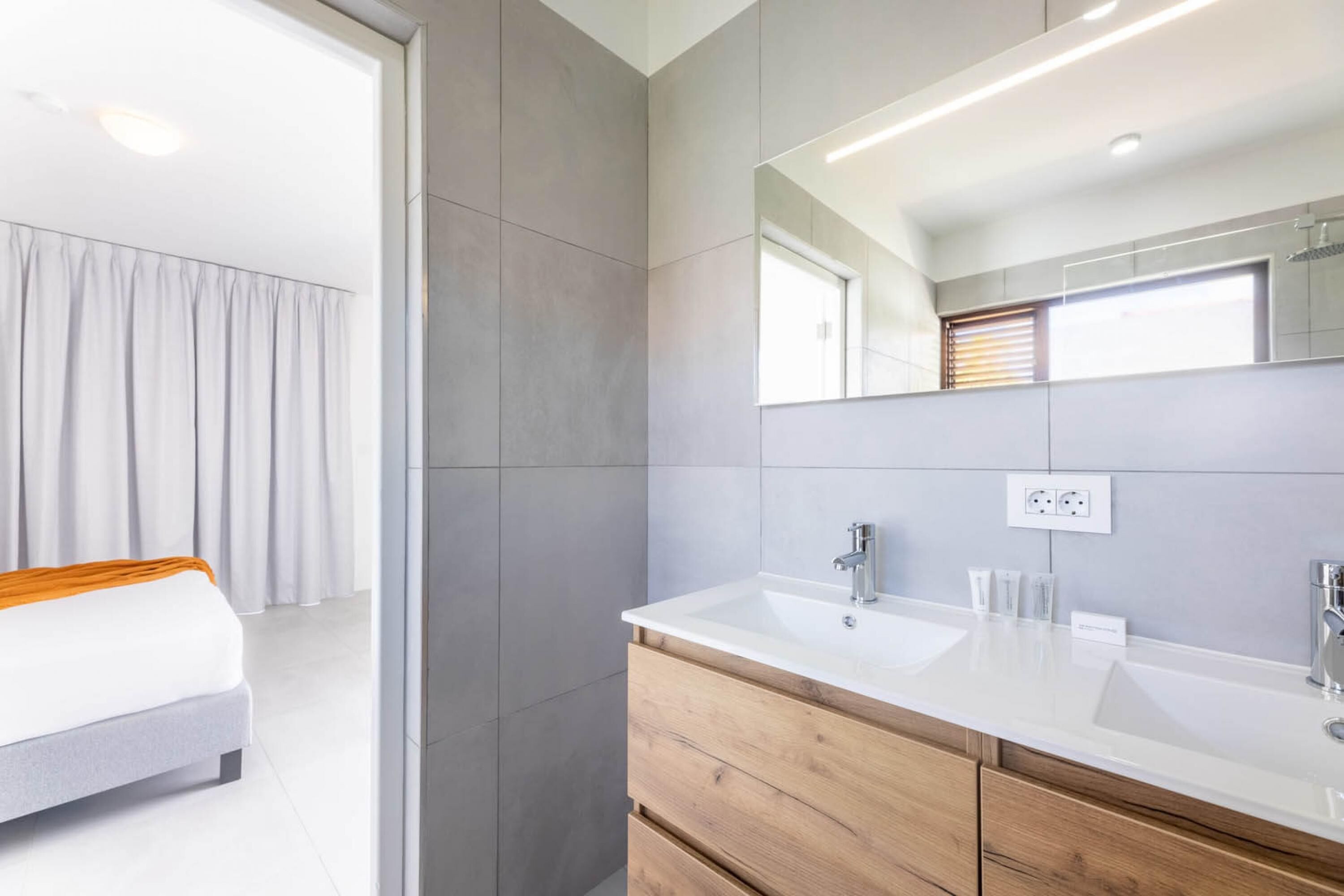 Ein modernes Badezimmer mit einem großen Spiegel, zwei Waschbecken und einer Holzausstattung.