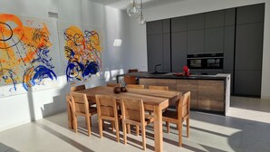A modern kitchen with dark cabinetry, a central island, and a dining area with wooden furniture. - Moderne villa, met artistieke inrichting. dicht bij wandelpaden, zee, golfgebied (Vera)