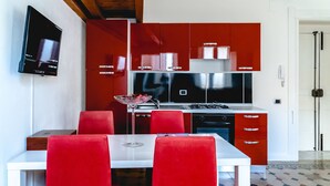 A modern kitchen with red cabinets, a white dining table, and red chairs.