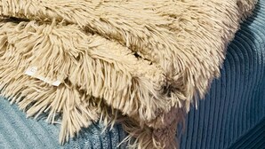 A bed with a textured beige blanket and blue upholstered headboard and footboard. - Ferienwohnung Gerberstein (Ruhla)