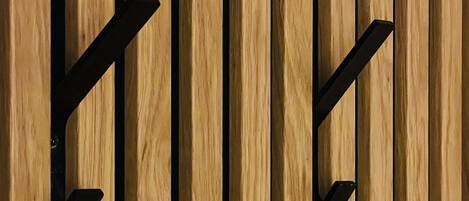 Un mur en bois composé de planches verticales et orné de deux crochets en métal noir.