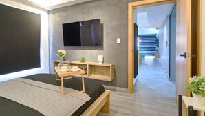 Ein modernes Schlafzimmer mit Bett, Nachttisch und einem Wand-Fernseher.
