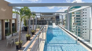 Ein Dachpool mit Glasabgrenzung, umgeben von Topfpflanzen und einer Sitzgelegenheit.
