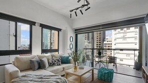 Ein modernes Wohnzimmer mit Sofa, Couchtisch und einem Balkon mit Stadtblick.