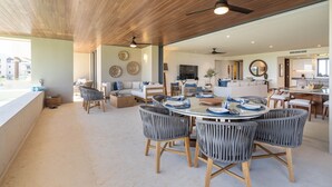 A spacious living area with a wooden ceiling, a dining table with chairs, and a kitchen in the background. - Lux Ocean & Bay Views, Full Access, 2 Golf Carts, Plunge Pool, Cook/Cleaning (Punta de Mita)
