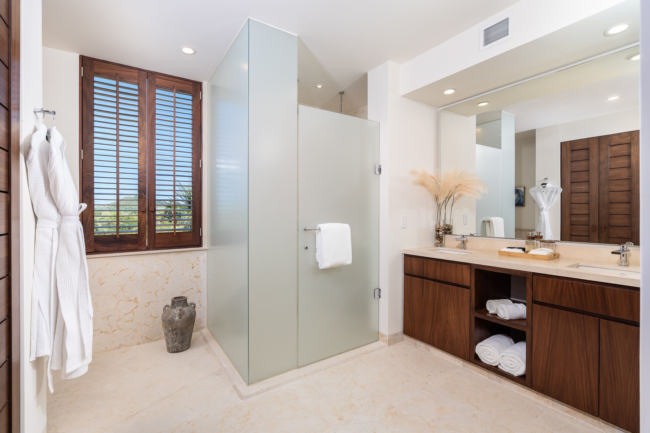 Un baño moderno con cabina de ducha de vidrio, armarios de madera y un espejo grande.