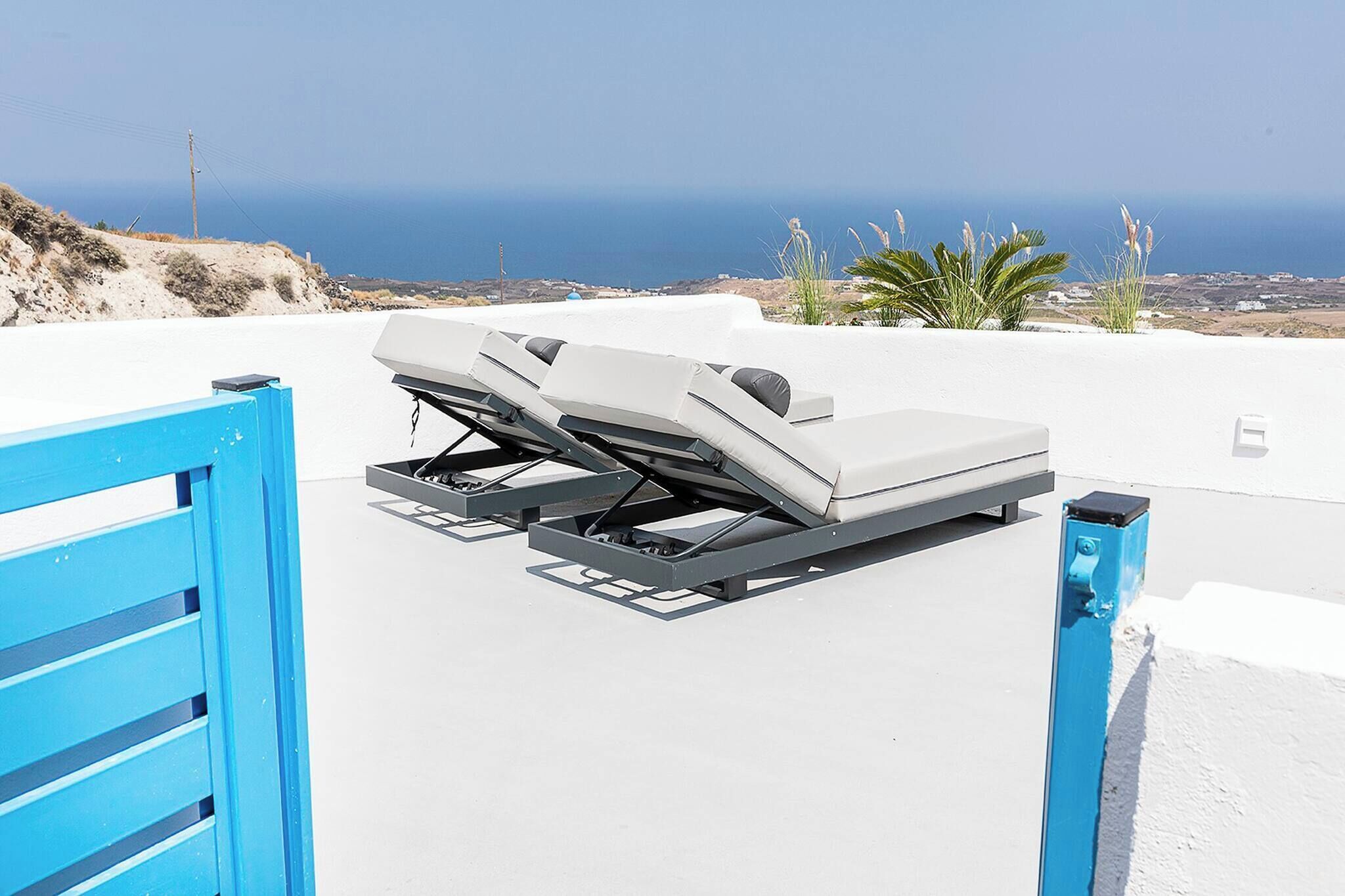 Ein Hotel am Strand mit weißer Fassade, einem blauen Tor und Blick auf das Meer.