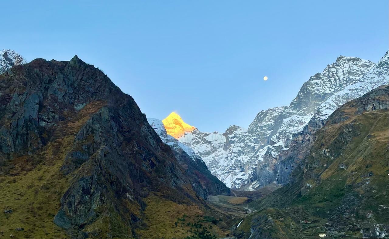 A mountainous landscape with a clear sky and a visible moon.