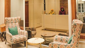 A modern interior with patterned armchairs, a round table, and a large mirror reflecting the room. - New Hotel Snow Crest (Joshimath)