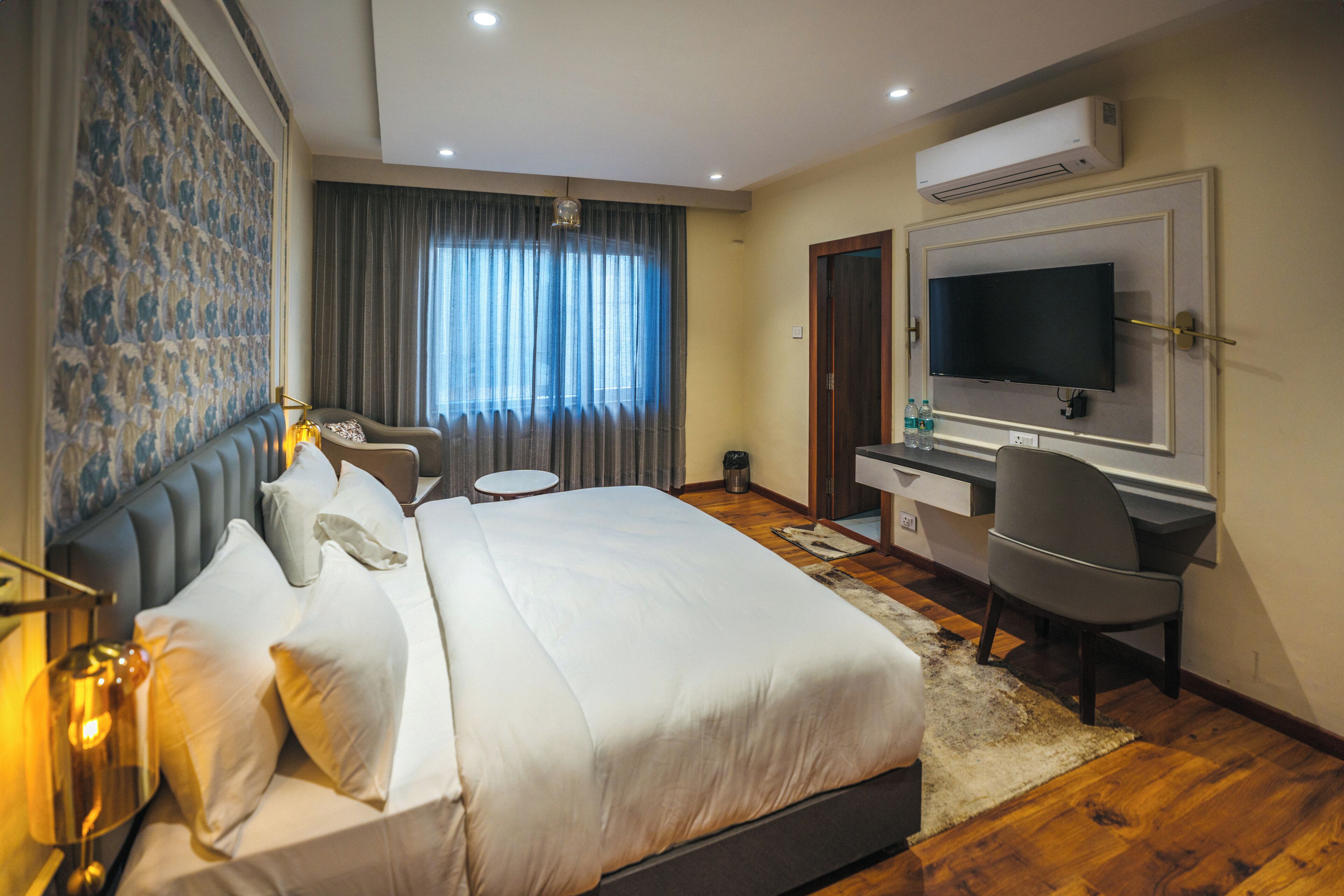 Habitación de hotel con una cama grande, un escritorio con silla, un televisor y un equipo de aire acondicionado.