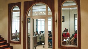 A hotel lobby with a staircase, arched windows, and hanging chandeliers. - New Hotel Snow Crest (Joshimath)