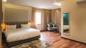 A hotel room with a large bed, a chair, a small table, and a mirror. - New Hotel Snow Crest (Joshimath)