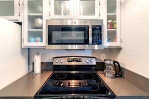 A kitchen with a stainless steel microwave, double oven, and a coffee maker on the counter.