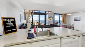 Een moderne keuken met een groot eiland, een spoelbak en een welkomstbord.
