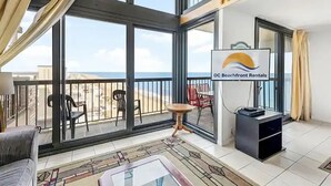 Ein geräumiger Balkon mit freiem Blick auf den Strand, ausgestattet mit Stühlen und einem Tisch.