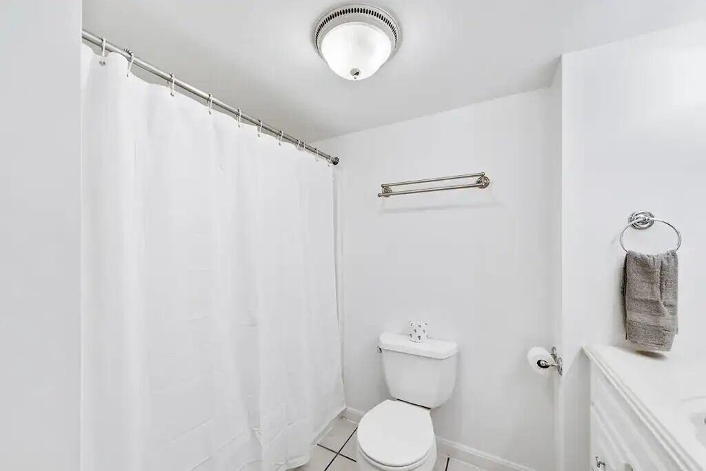 Ein Badezimmer mit Duschvorhang, Toilette, Handtuchhalter und einem Handtuch an der Wand.