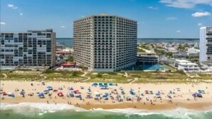 Een strandhotel met meerdere verdiepingen, een zandstrand ervoor en een helder uitzicht op de oceaan.