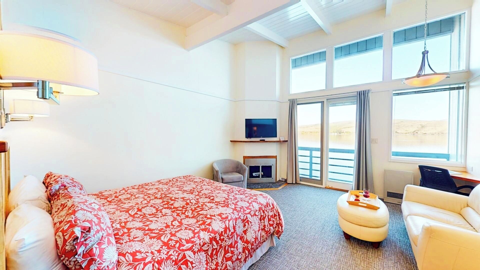 Hotellihuone, jossa on suuri sänky, sohva, nojatuoli, televisio ja takka.
