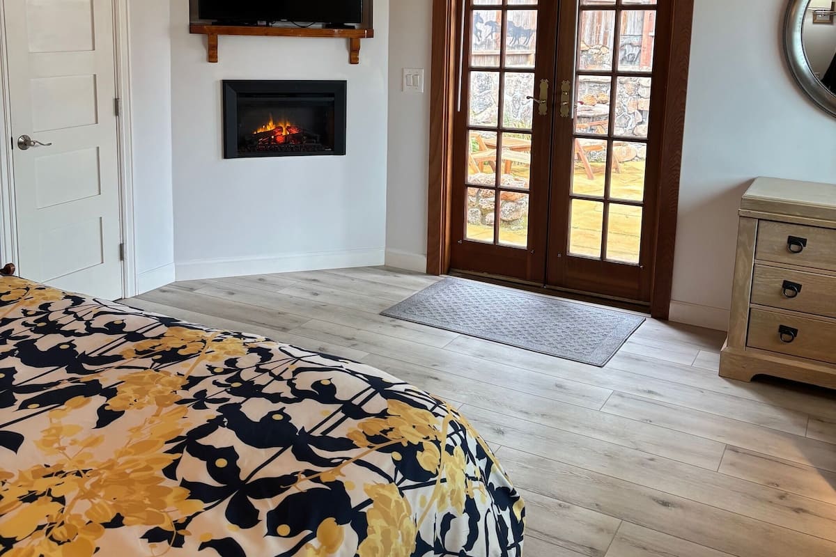 Une chambre à coucher comprenant un lit, une cheminée, un téléviseur et une porte donnant sur un balcon.