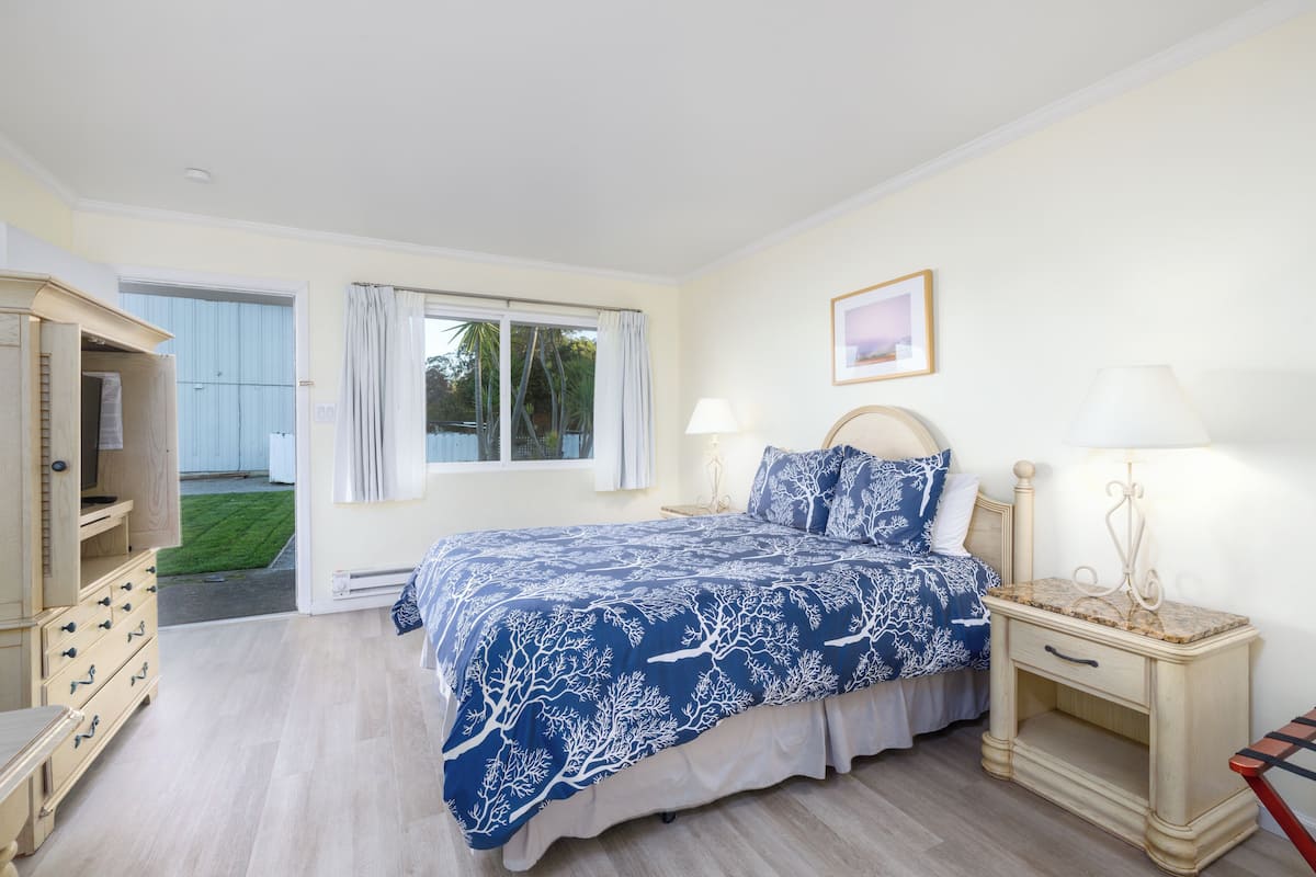 Une chambre à coucher avec un lit, des tables de chevet, une commode et une fenêtre avec des rideaux.