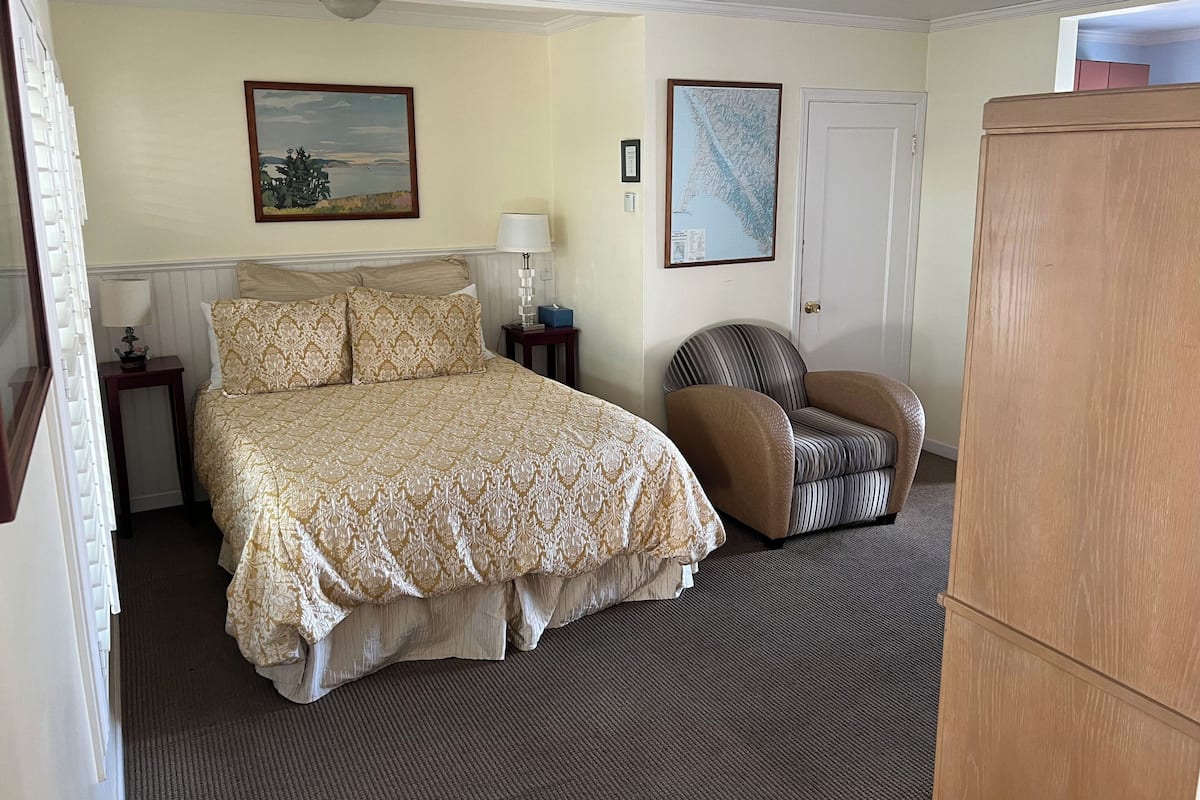 Une chambre d’hôtel avec un lit, une chaise, un bureau et une armoire.